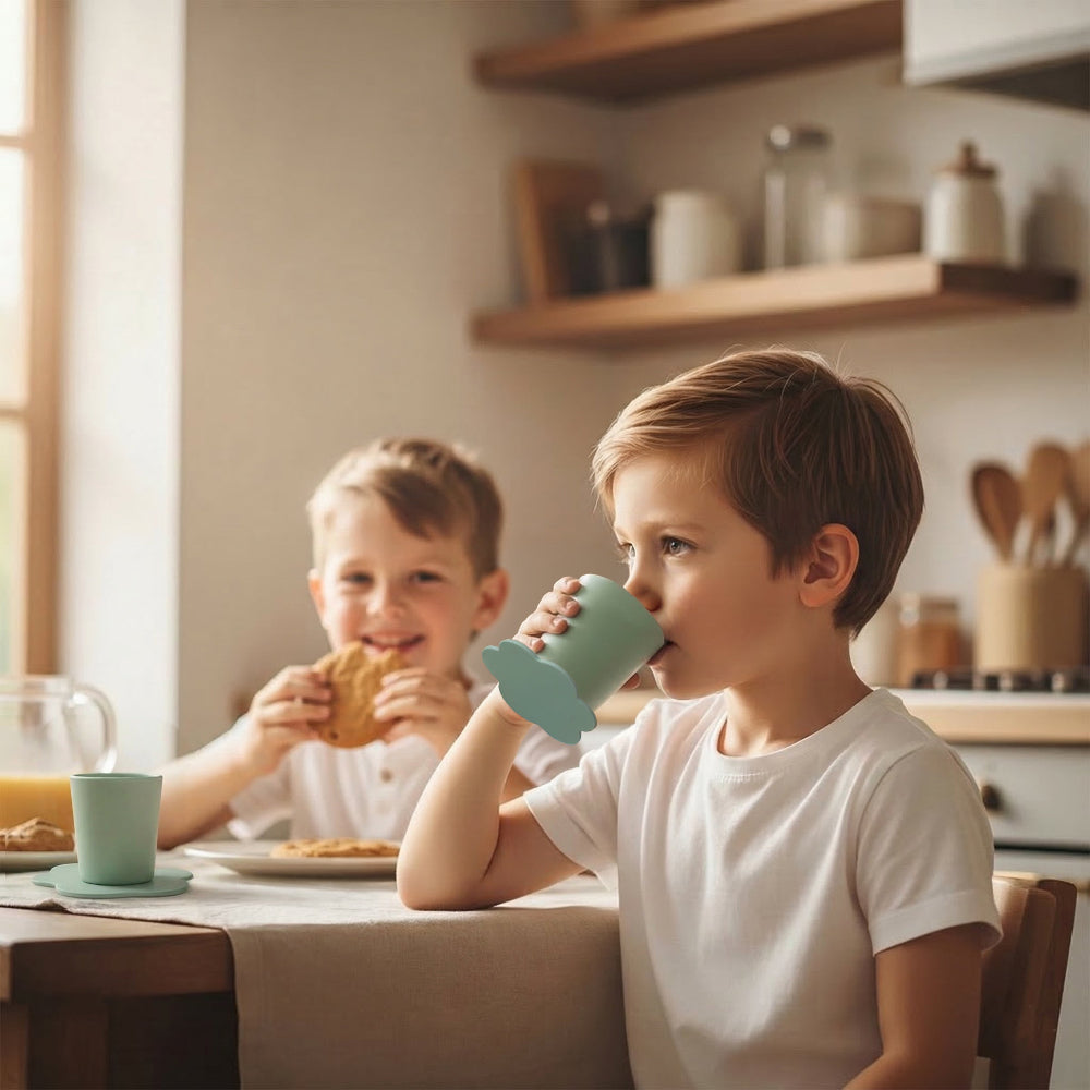 twee kinderen drinken uit STEDDI anti-omval kinderbekers tijdens eten aan tafel