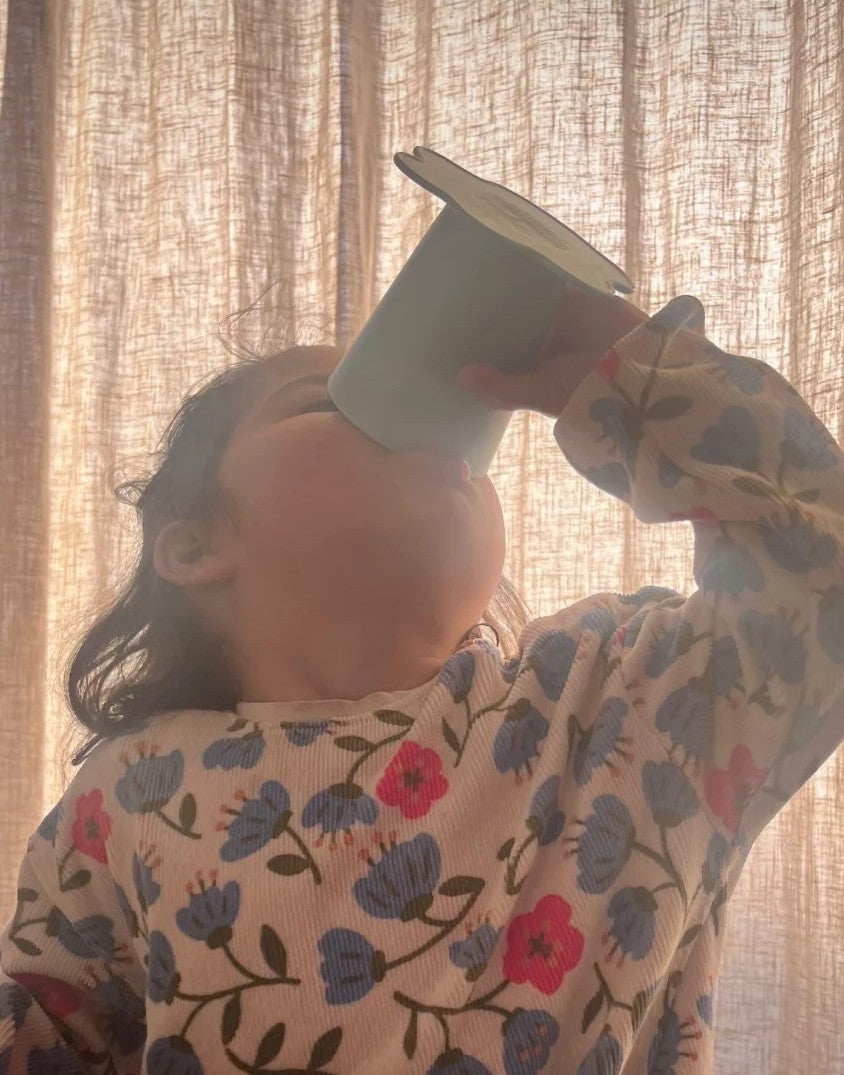 Peuter leert drinken uit een open beker zonder tuit